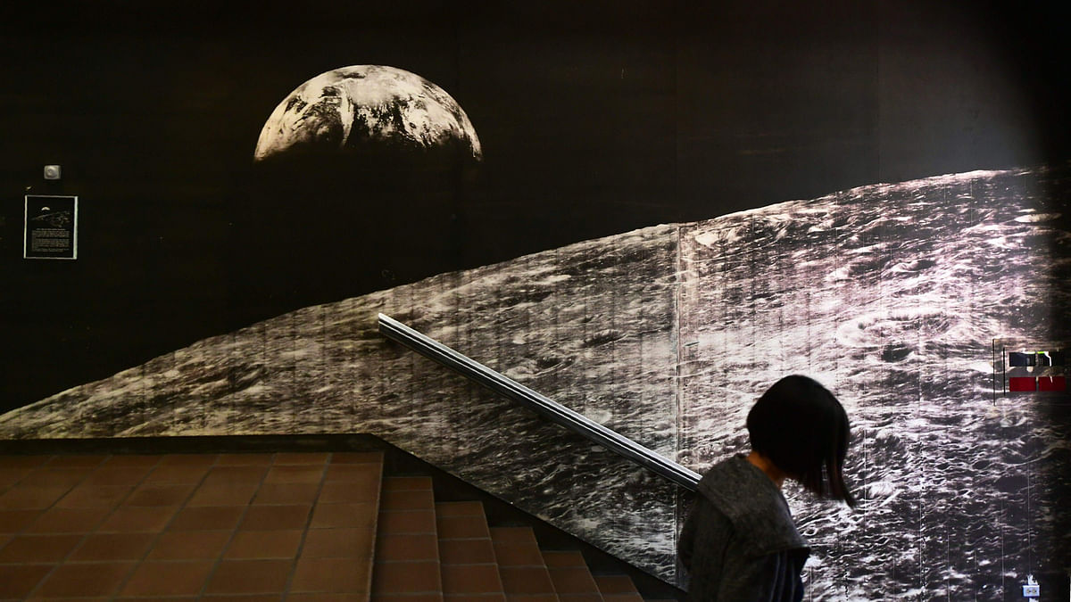 A woman walks past a wall sized image of the `First View Of Earth From The Moon` at the California Institute of Technology (Caltech) Seismological Laboratory in Pasadena, California on June 1, 2017. AFP