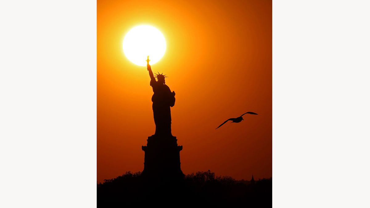 The sun sets behind the Statue of Liberty as a seagull flies past on June 02, 2017 in New York City. AFP