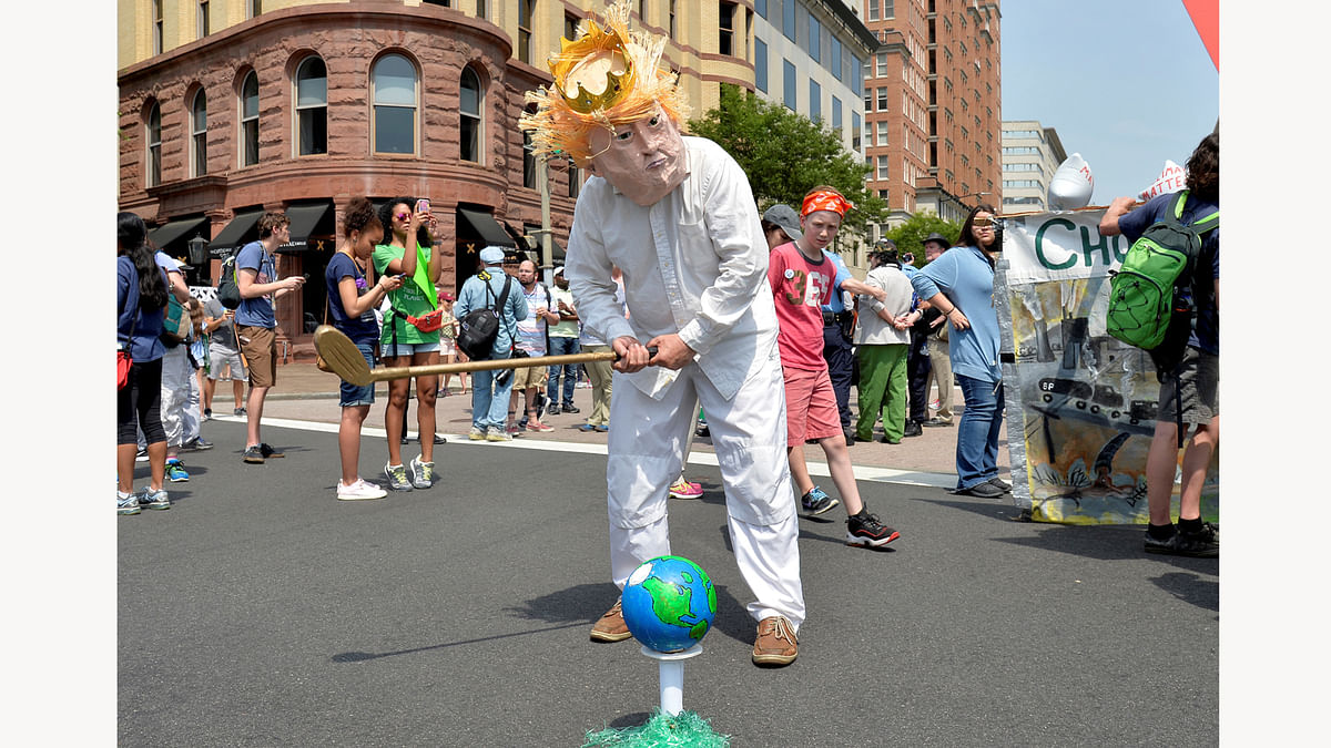 A protester in a costume depicting Trump sets an Earth on a tee as he holds a golf club while joining demonstrators moving down Pennsylvania Avenue during a People`s Climate March, to protest U.S. President Donald Trump`s stance on the environment, in Washington, U.S., April 29, 2017. REUTERS