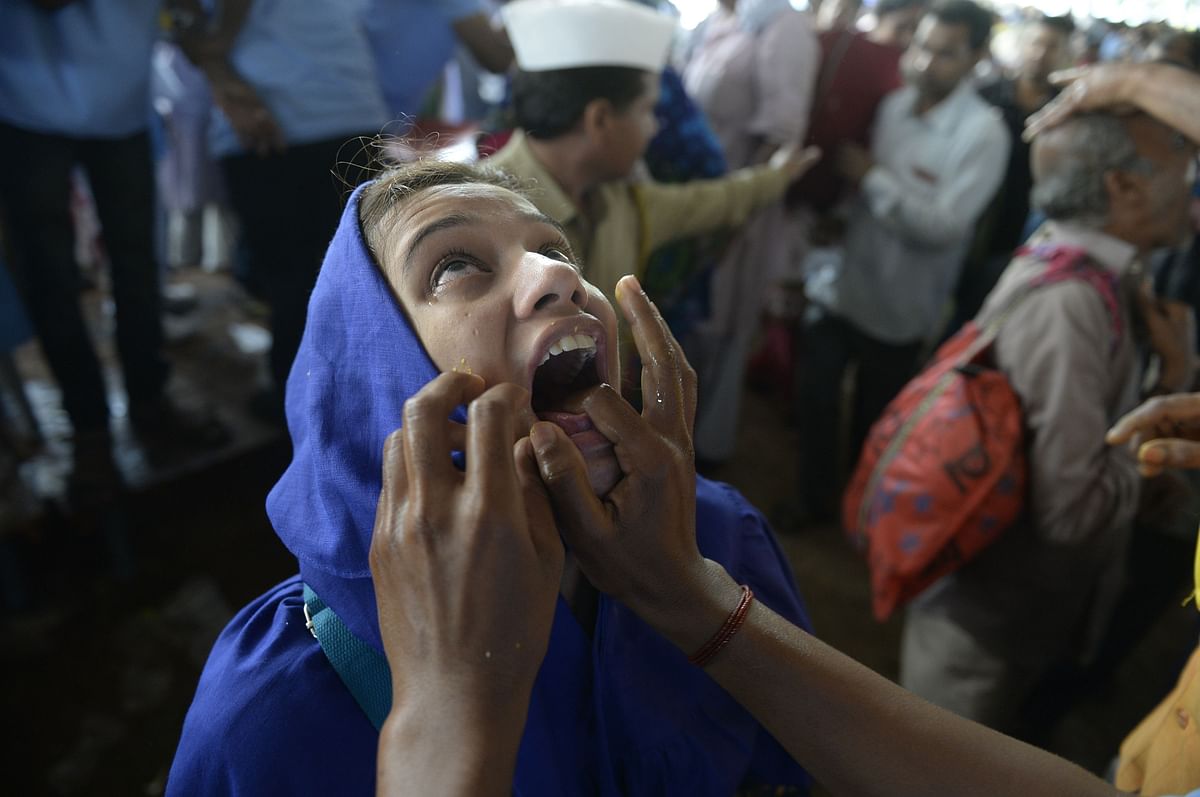 An Indian woman reacts after being administered `fish medicine` by a member of the Bathini Goud family at the exhibition grounds in Hyderabad on June 8, 2017.  AFP