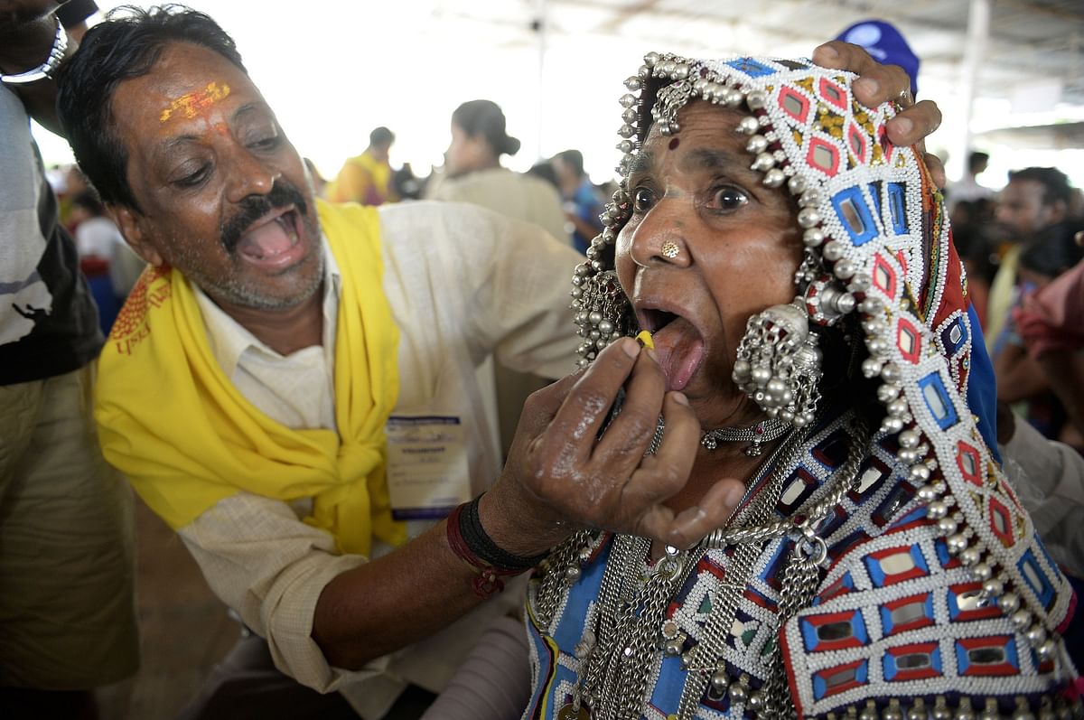 An Indian member of the Bathini Goud family (L) administers `fish medicine` to a Lambadi Tribal woman patient at the exhibition grounds in Hyderabad on June 8, 2017. AFP