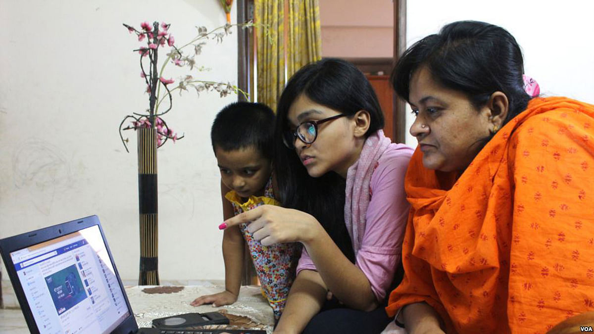 A young school girl in Dhaka, Bangladesh, is teaching her mother how to use Facebook. Photo: VOA