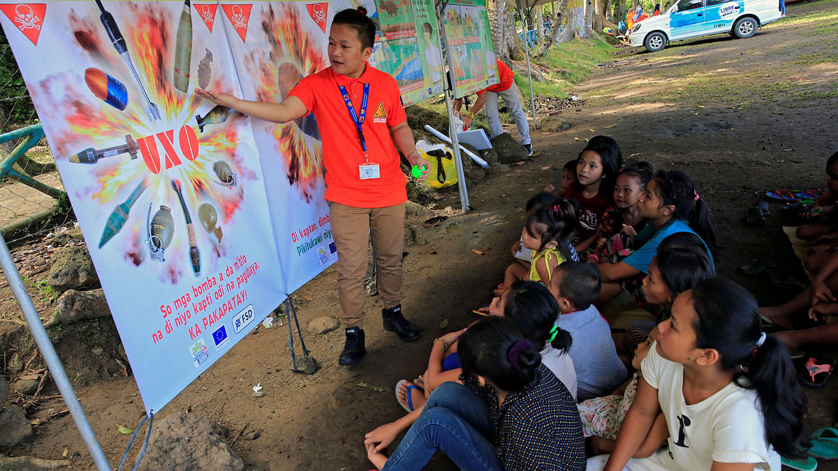 A government worker explains a poster displaying different kinds of bombs during an Unexploded Ordnance briefing to children who have left their houses with their families to escape intense fighting between government forces and insurgents from Maute group, who have taken over parts of Marawi city, at the evacuation centre in Iligan city. Reuters