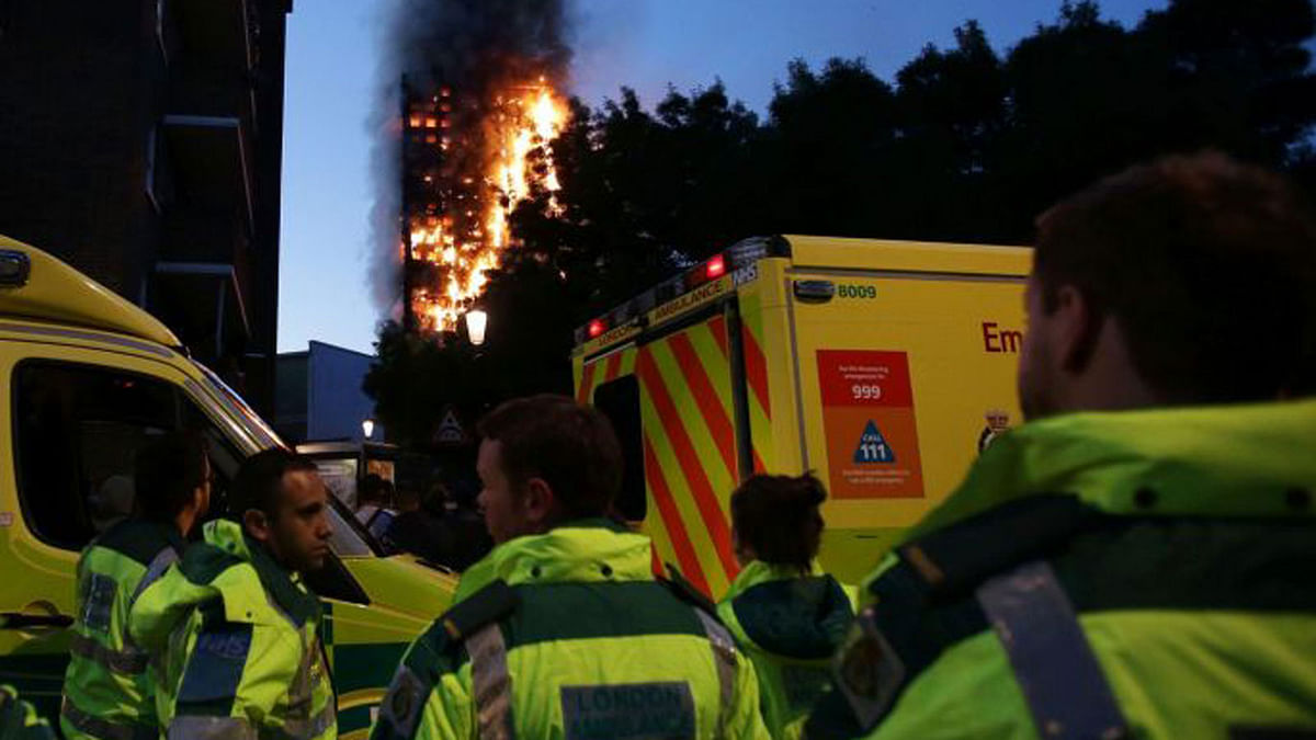 Members of the emergency services watch as Grenfell Tower is engulfed by fire. Photograph: AFP