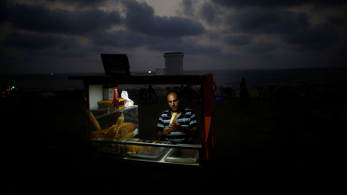 A Palestinian vendor sells snacks on a beach during a power cut as he uses battery-powered lights in Gaza City, July 12, 2017. Reuters