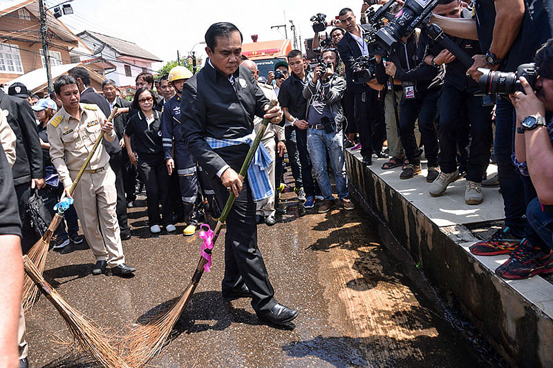 This handout from the Prime Minister`s Office taken and received on August 2, 2017 shows Thailand`s Prime Minister Prayut Chan-O-Cha using a ceremonial broom to help clean a street in a town in the province of Sakon Nakhon in northeastern Thailand, after it was hit by floods. Heavy rains have brought some of the worst floods in years to Thailand`s rural northeast where 23 people have died over the past month, officials said on August 2.
