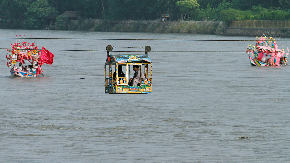 Local tourists use a cable car and boats to cross the Sardaryab river in Charsadda, Pakistan 1 August. Photo: Reuters