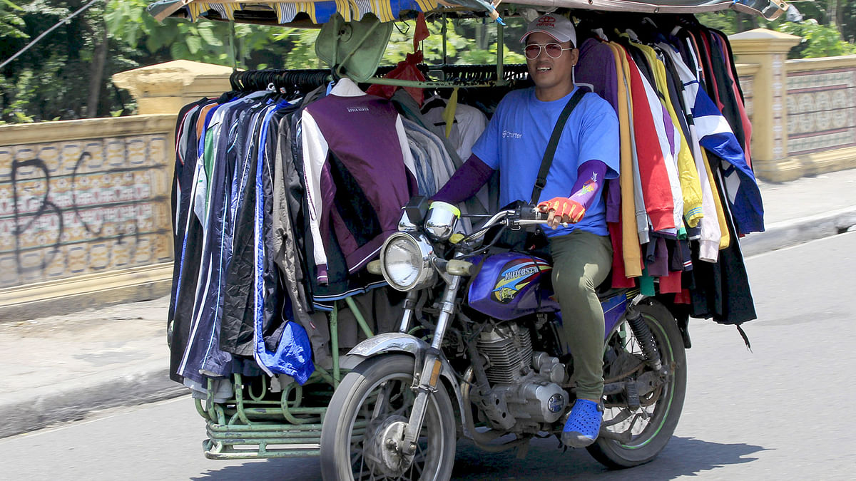 A man rides a motorcycle cab filled with used clothing which he sells along a main street in Manila. Reuters