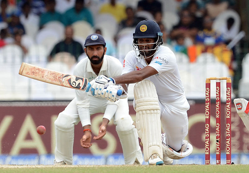 Sri Lankan cricketer Dimuth Karunaratne ® is watched by Indian cricketer Cheteshwar Pujara as he plays a shot during the fourth day of the second Test match between Sri Lanka and India at the Sinhalese Sports Club (SSC) Ground in Colombo. Photo: AFP