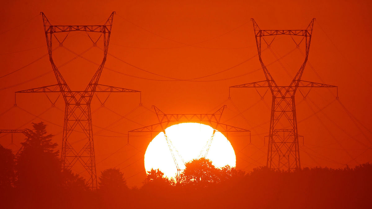 The sun rises behind pylons of high-tension electricity power lines outside Longnes, near Paris, France, 6 August, 2017. Photo: Reuters