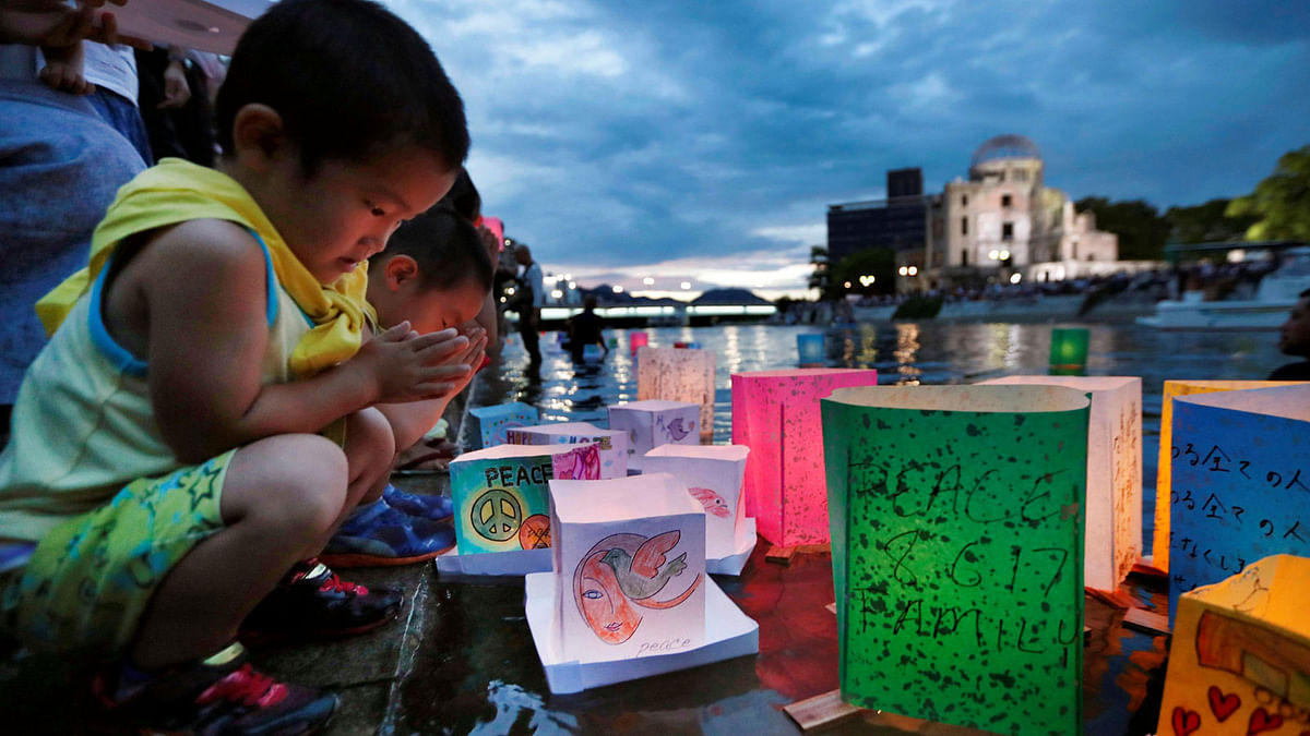 Children pray after releasing paper lanterns on the Motoyasu river facing the Atomic Bomb Dome in remembrance of atomic bomb victims on the 72nd anniversary of the bombing of Hiroshima, western Japan, 6 August, 2017. Photo: Reuters