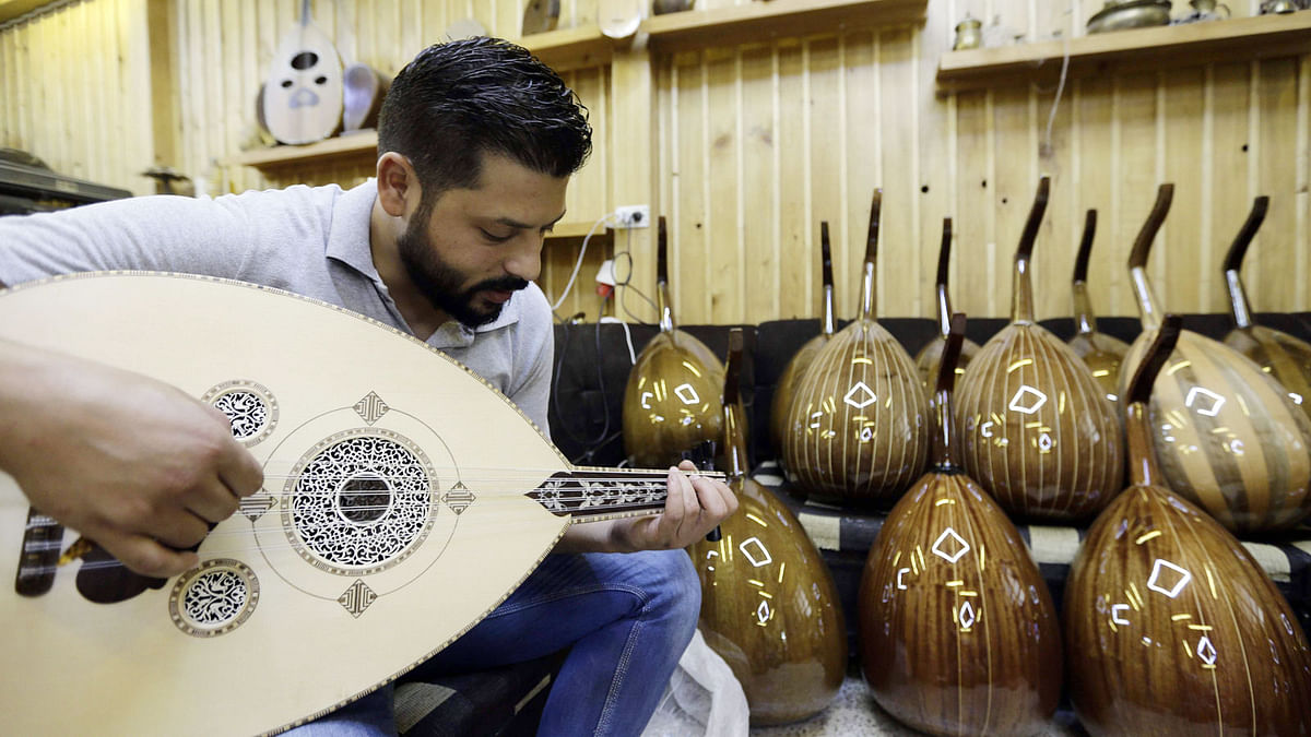 Ali Khalifeh, a lute-maker, tries a oud at a shop in the Syrian capital Damascus on 17 July, 2017. Photo: AFP