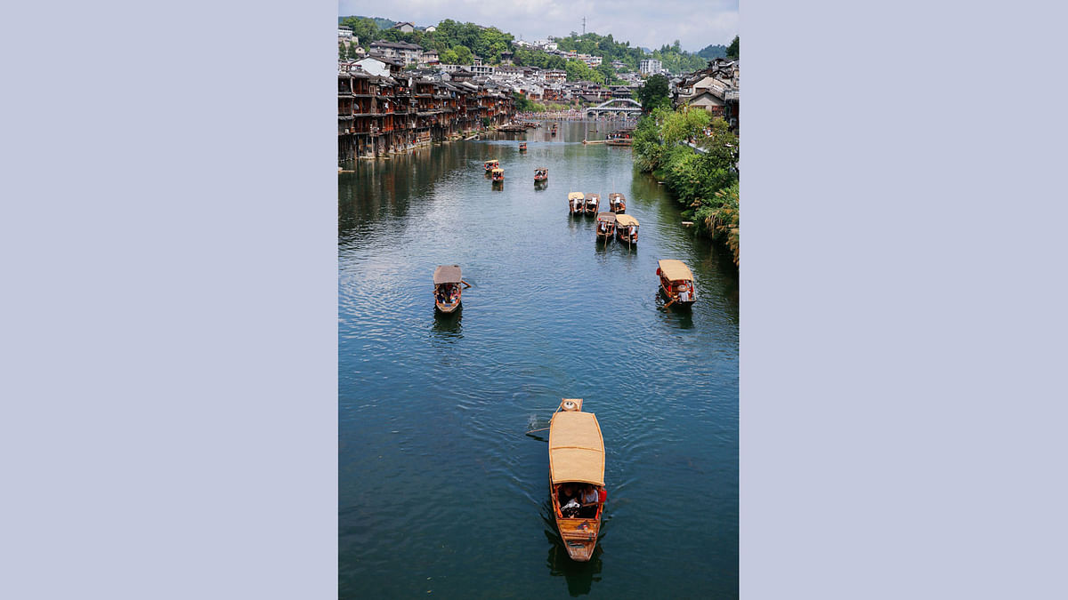 This photo taken on August 5, 2017 shows tourists riding boats on the Tuojiang River in the ancient town of Fenghuang in Xiangxi, in China`s central Hunan province. AFP