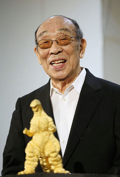 In this picture taken on 19 July, 2014, Japanese actor Haruo Nakajima speaks behind a gold statue of Godzilla at a Godzilla exhibition in Tokyo. Photo: AFP