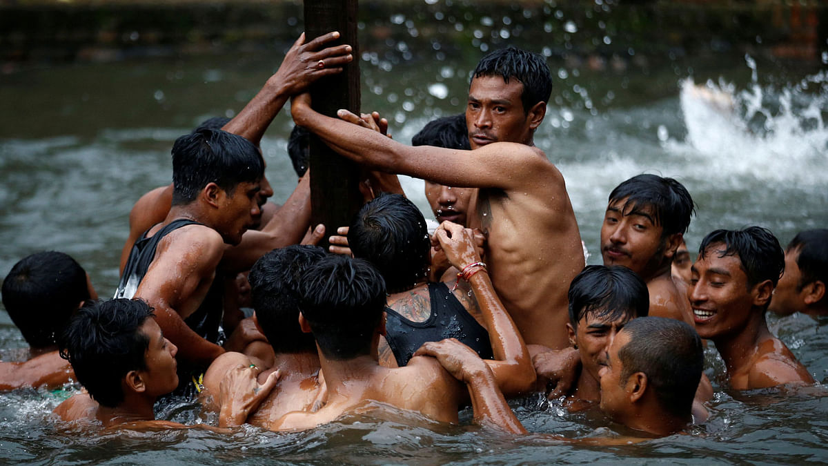 Devotees gather in between the pond as they submerge a goat in the water while competing to retrieve it during the Deopokhari festival in Khokana, Nepal 9 August, 2017. Photo: Reuters