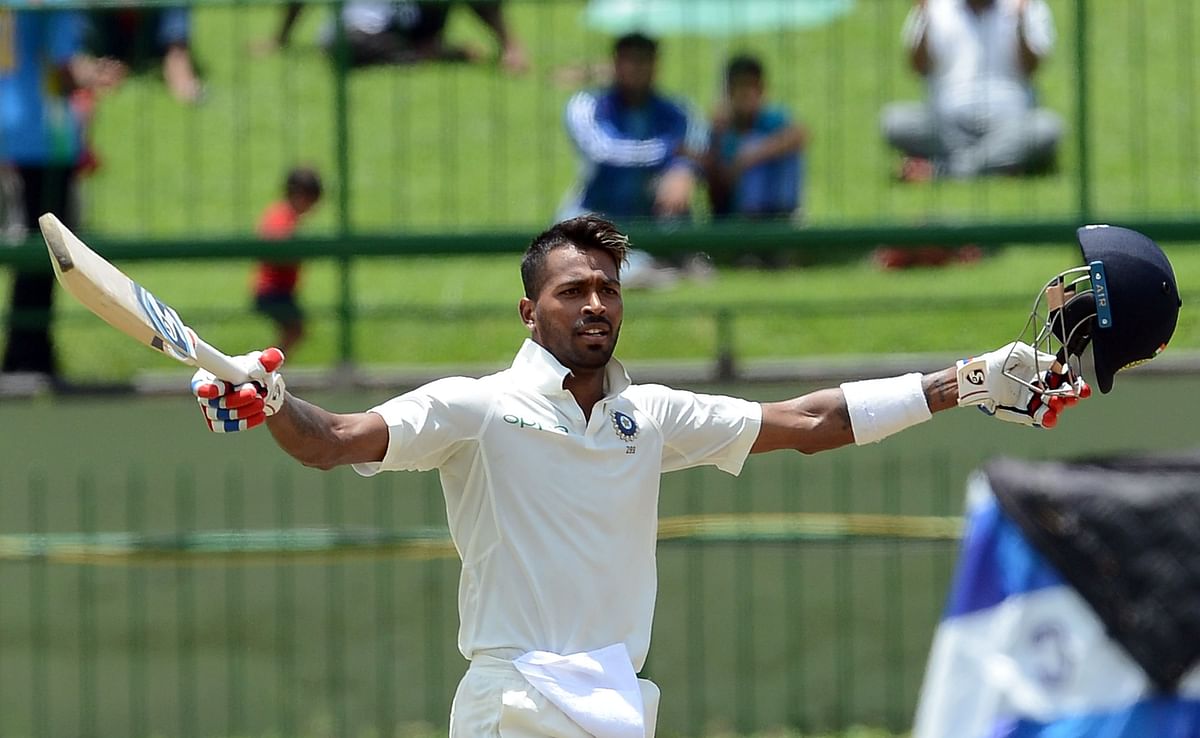 India's Hardik Pandya raises his bat and helmet in celebration after scoring a century during the second day of the third and final Test match between Sri Lanka and India at the Pallekele International Cricket Stadium in Pallekele on 13 August, 2017. Photo: AFP