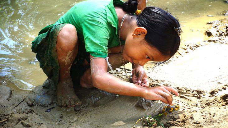 A child plays with mud and water on her own near a hilly stream in Mirsarai upazila of Chittagong. Photo: Iqbal Hossain.