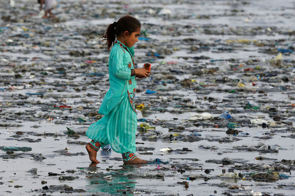 A girl walks through rubbish left by sea waves along Clifton beach in Karachi, Pakistan on 5 September 2017. Photo: Reuters
