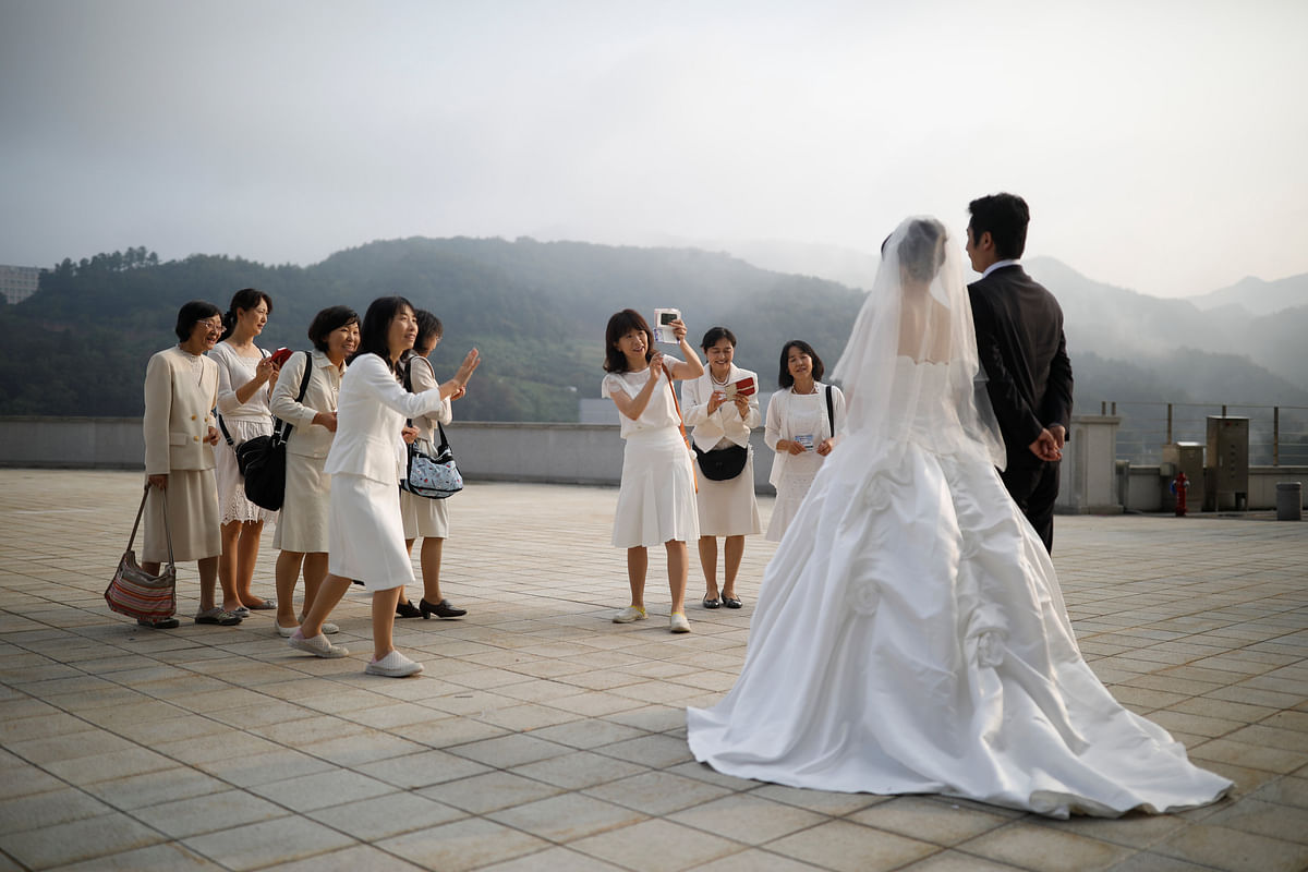 Relatives take photographs of a newlywed couple before a mass wedding ceremony of the Unification Church at Cheongshim Peace World Centre in Gapyeong, South Korea on 7 September 2017. Photo: Reuters