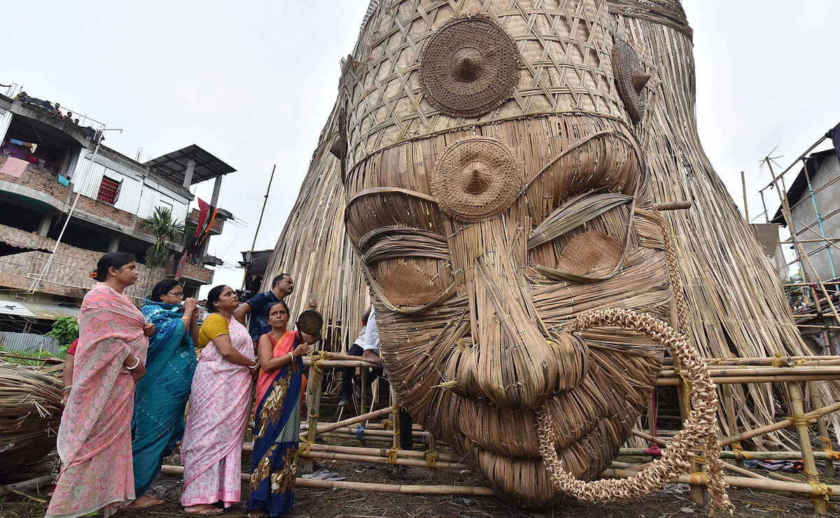 Indian Hindu devotees offering prayers to the head of a 100-foot bamboo idol of the Hindu deity Durga in Guwahati, in honour of the Durga Puja festival. The 100ft idol of Durga is aimed at breaking the Guinness World Records for the tallest bamboo sculpture. Photo: AFP