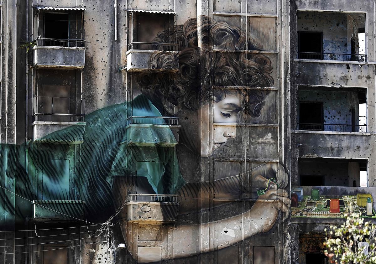 Graffiti of a boy working on an electronic device is seen on a building riddled with holes from shrapnel dating back from the Lebanese civil war (1975-1990) in Beirut on 26 September 2017. Photo: AFP