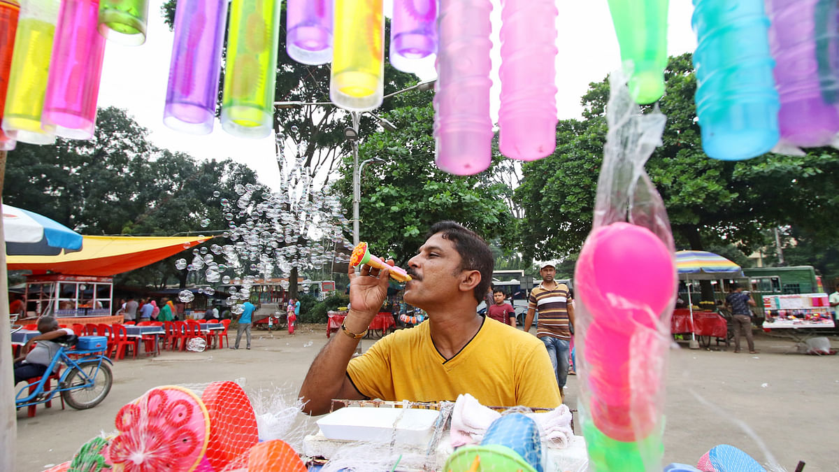 Toy vendor blows bubbles to attract the little ones in front of Shishu Park in the capital city. Photo: Saiful Islam
