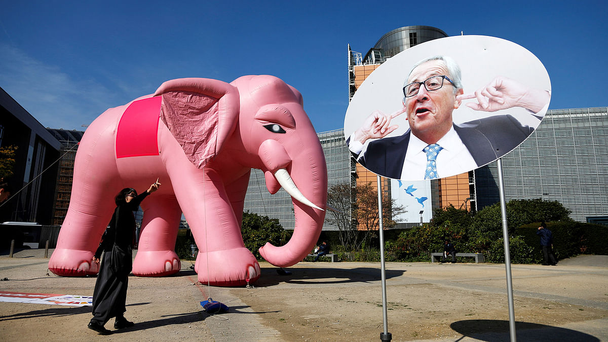 An inflatable pink elephant is pictured next to a sign depicting EU Commission President Juncker covering his ears during a protest by environmental activists in Brussels. Reuters