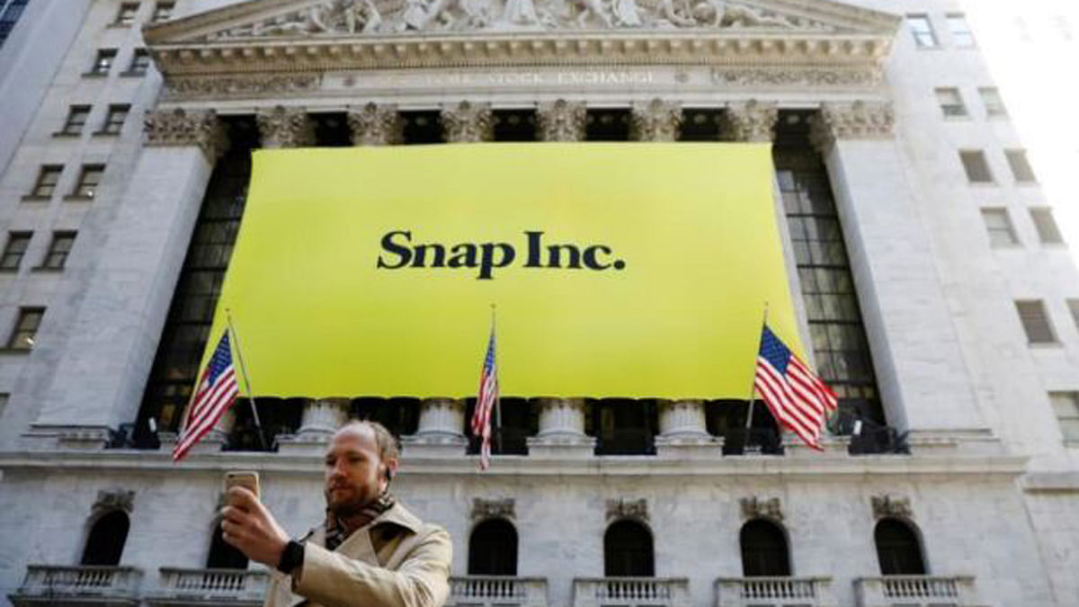 A man takes a photograph of the front of the New York Stock Exchange (NYSE) with a Snap Inc. logo hung on the front of it shortly before the company`s IPO in New York, U.S., March 2, 2017. Photo: REUTERS