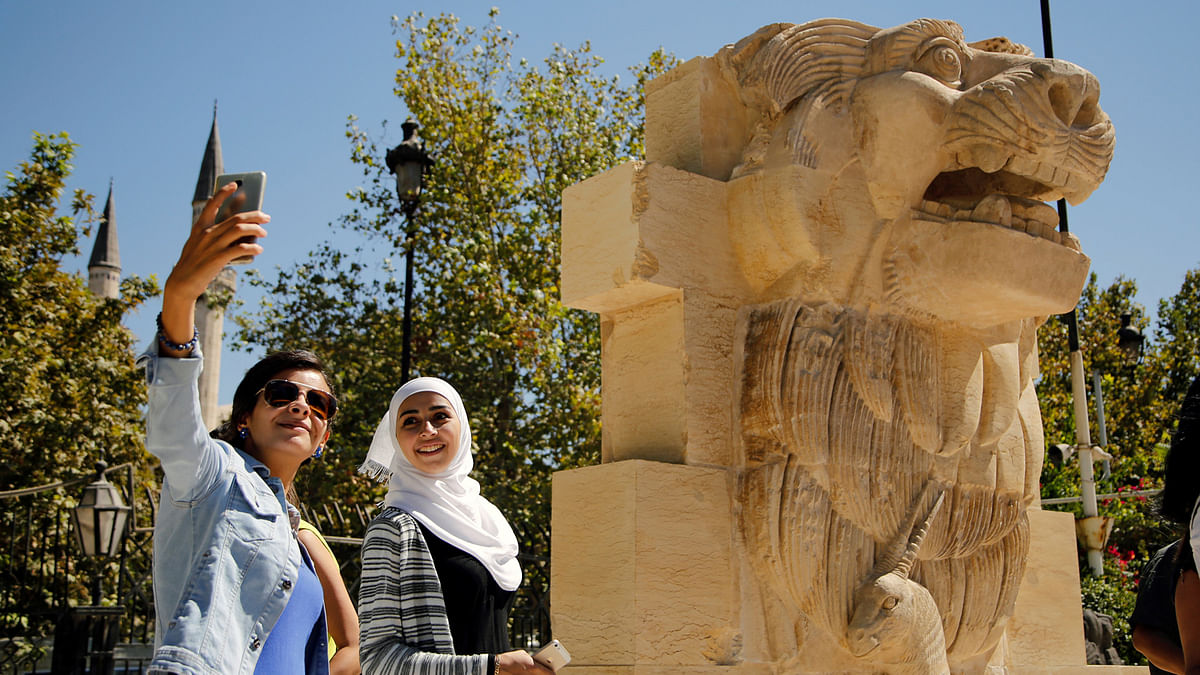 Syrian women take selfies in front of the restored Lion of al-Lat, a 2,000-year old statue, on display in Damascus, Syria 1 October 2017.  Photo: Reuters