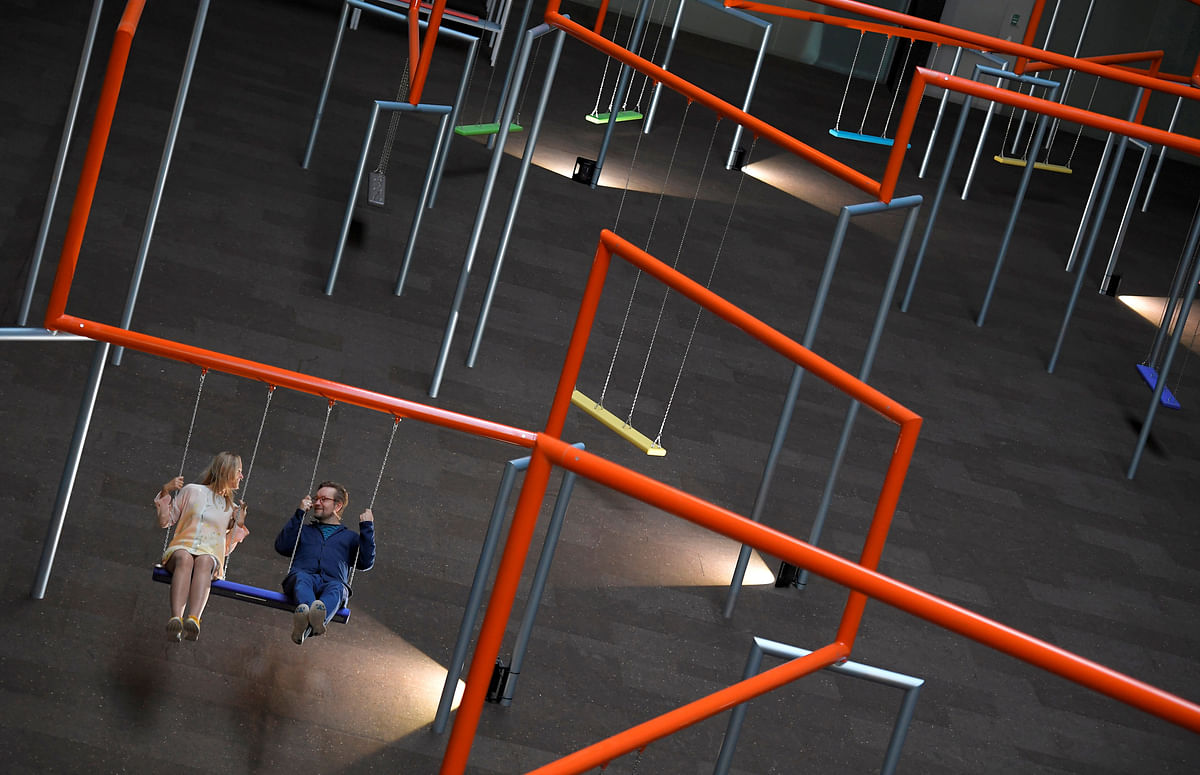 Two visitors ride on swings which form part of the new installation `One Two Three Swing!` by Danish art collective SUPERFLEX, at the Tate Modern in London, Britain, 2 October 2017. Reuters