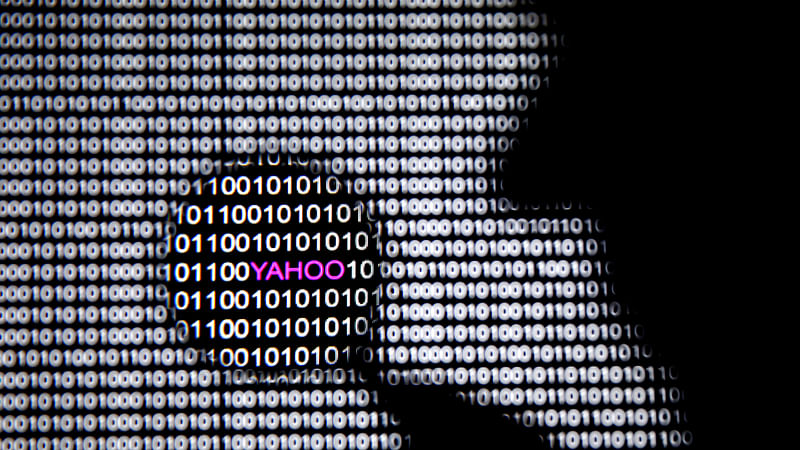 A photo illustration shows a man in front of a Yahoo logo seen through a magnifying glass in front of a displayed cyber code. Reuters file photo