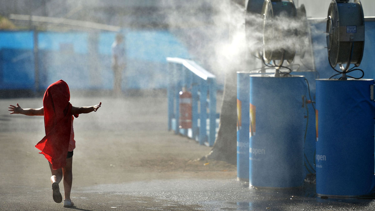 A young child cooling off by running past a set of vapour fans in Melbourne. AFP file photo