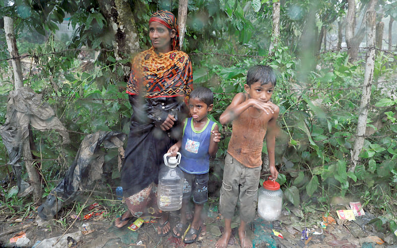 Rohingya refugees stand by the road in the rain outside their camp near Cox`s Bazar, Bangladesh, 3 October, 2017. Photo: Reuters