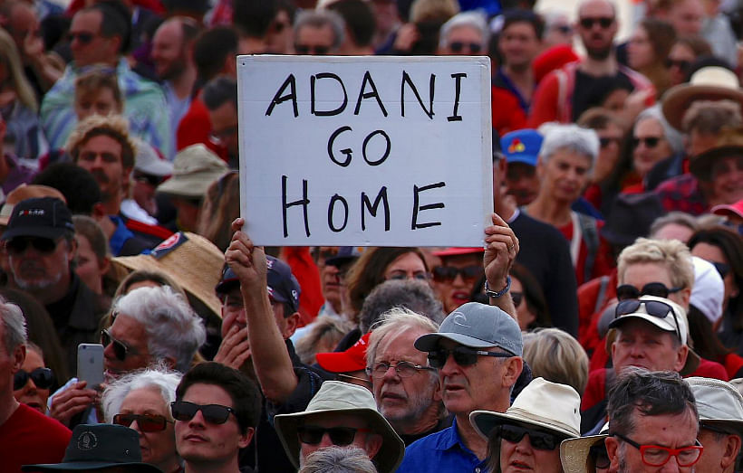 A protester holds a sign as he participates in a national Day of Action against the Indian mining company Adani`s planned coal mine project in north-east Australia, at Sydney`s Bondi Beach, on 7 October 2017. -- Reuters
