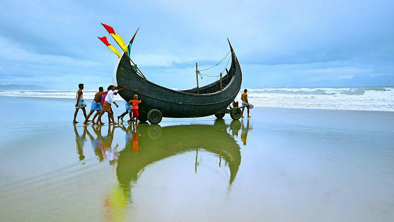Fishermen push a boat (locally called Sampan) into the sea. The photo was taken recently in the sea beach of Cox`s Bazar. Photo: Sabina Yesmin