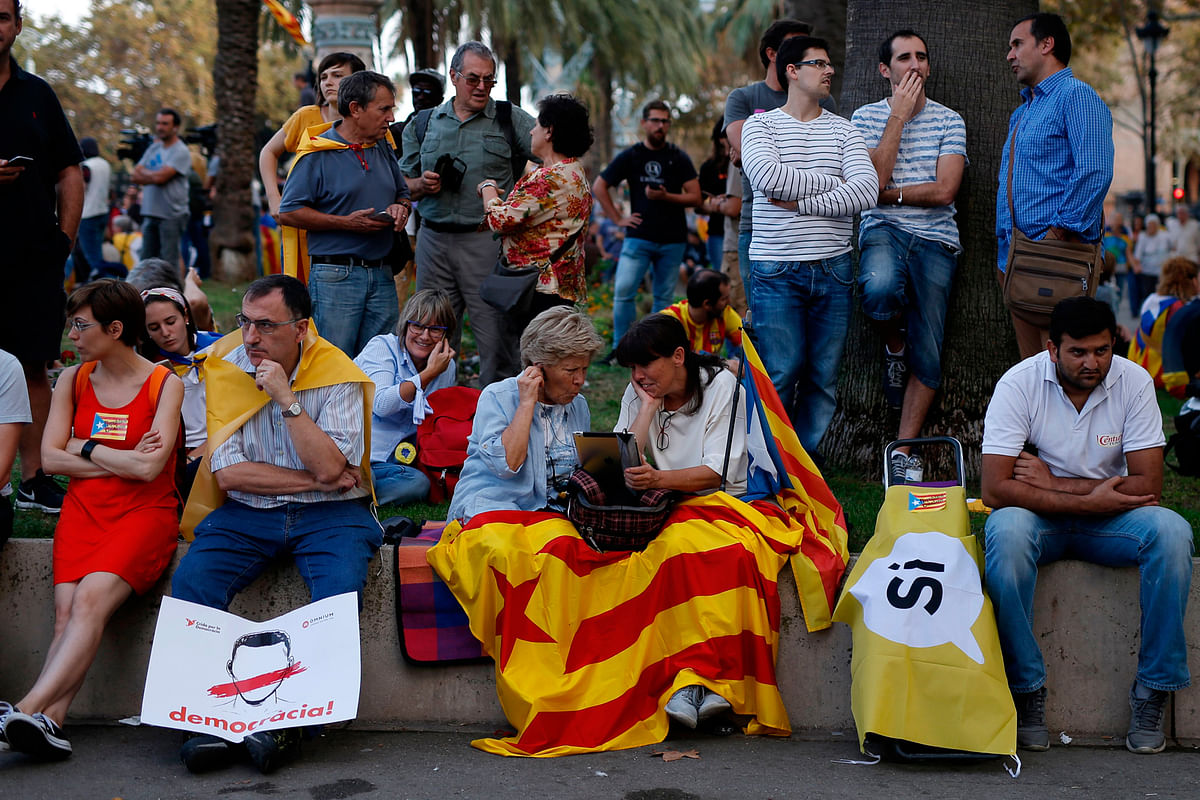 People with Esteladas (Pro-independence Catalan flag) and banners reading `YES` and `Democracy!` wait for the speech of Catalan regional government president Carles Puigdemont in Barcelona on 10 October, 2017 in Barcelona. Photo: AFP