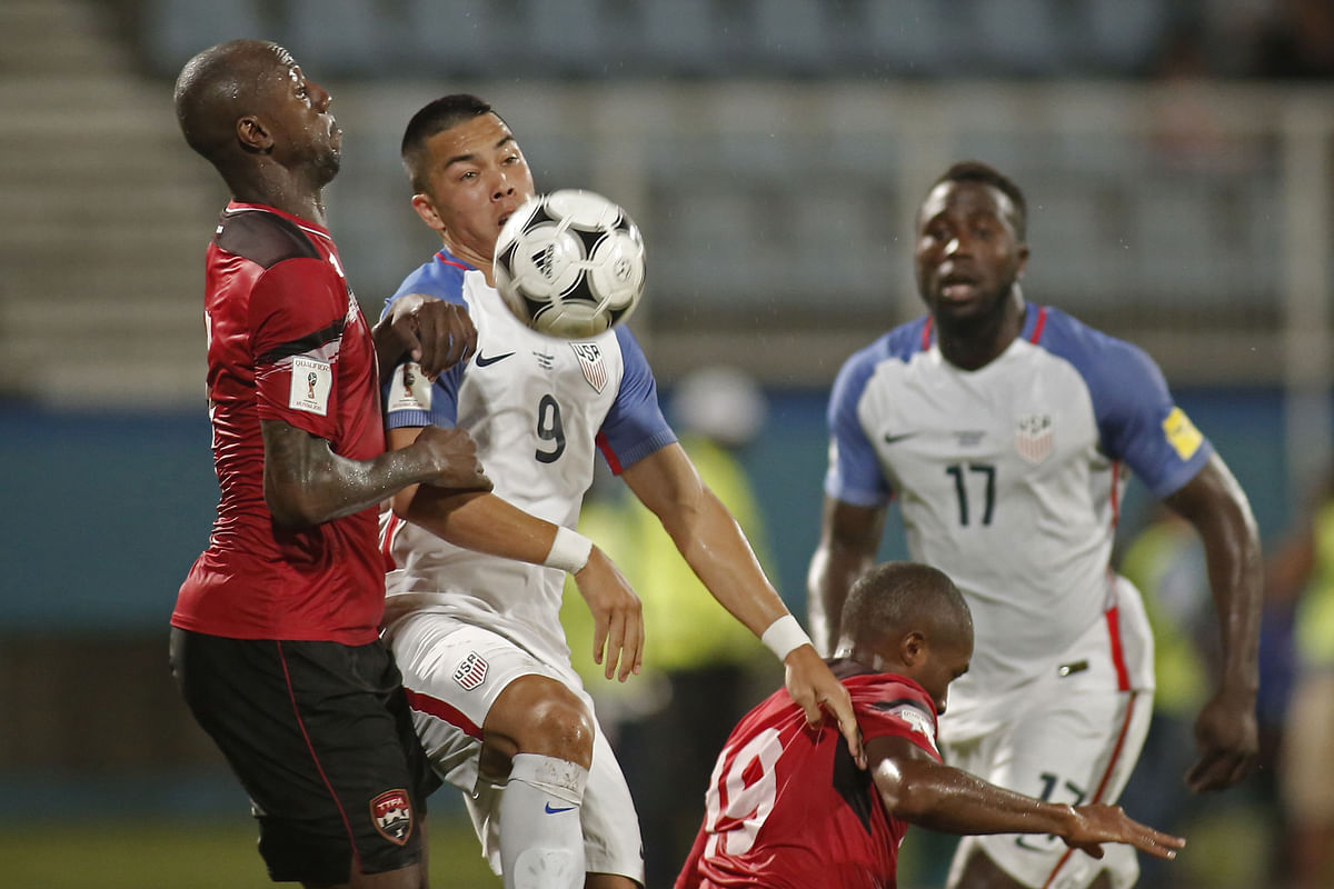 Trinidad and Tobago`s Daneil Cyrus (L) and USA`s Bobby Wood vie for the ball during their 2018 World Cup qualifier football match in Couva, Trinidad and Tobago, on October 10, 2017. AFP
