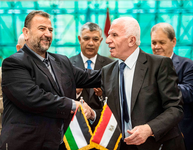 Fatah`s Azam al-Ahmad (R)and Saleh al-Aruri (L) of Hamas shake hands after signing a reconciliation deal in Cairo on 12 October, 2017, as the two rival Palestinian movements ended their decade-long split following negotiations overseen by Egypt. Photo: AFP
