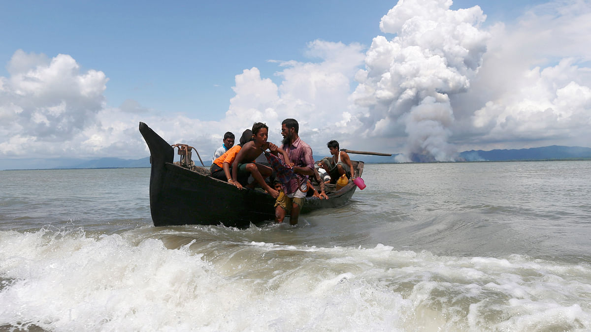 Smoke is seen on Myanmar`s side of border as a boat carrying Rohingya refugees arrives to the shore after crossing the Bangladesh-Myanmar border through the Bay of Bengal, in Shah Porir Dwip, Bangladesh, 11 September, 2017. Photo: Reuters