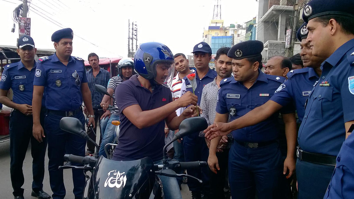 Gopalganj district police congratulates the motorcycle riders using helmet with flowers in old Launchghat area on 28 October 2017. Photo: Prothom Alo