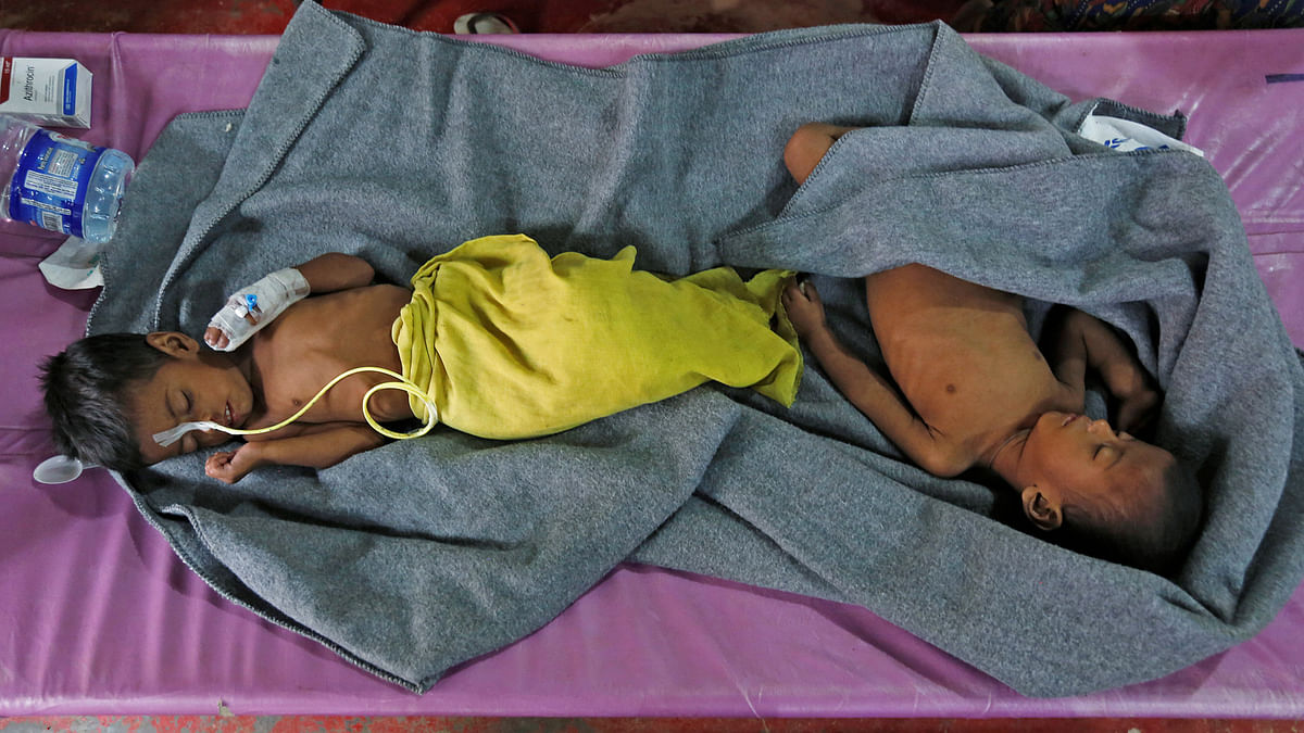 Ruaida Begum (L), 3, suffering from severe malnutrition, and her brother Nurul Amin, 1, suffering from pneumonia, lie on a bed at a diarrhoea treatment centre in Kutupalong refugee camp near Cox`s Bazar, Bangladesh on 28 October, 2017. Photo: Reuters