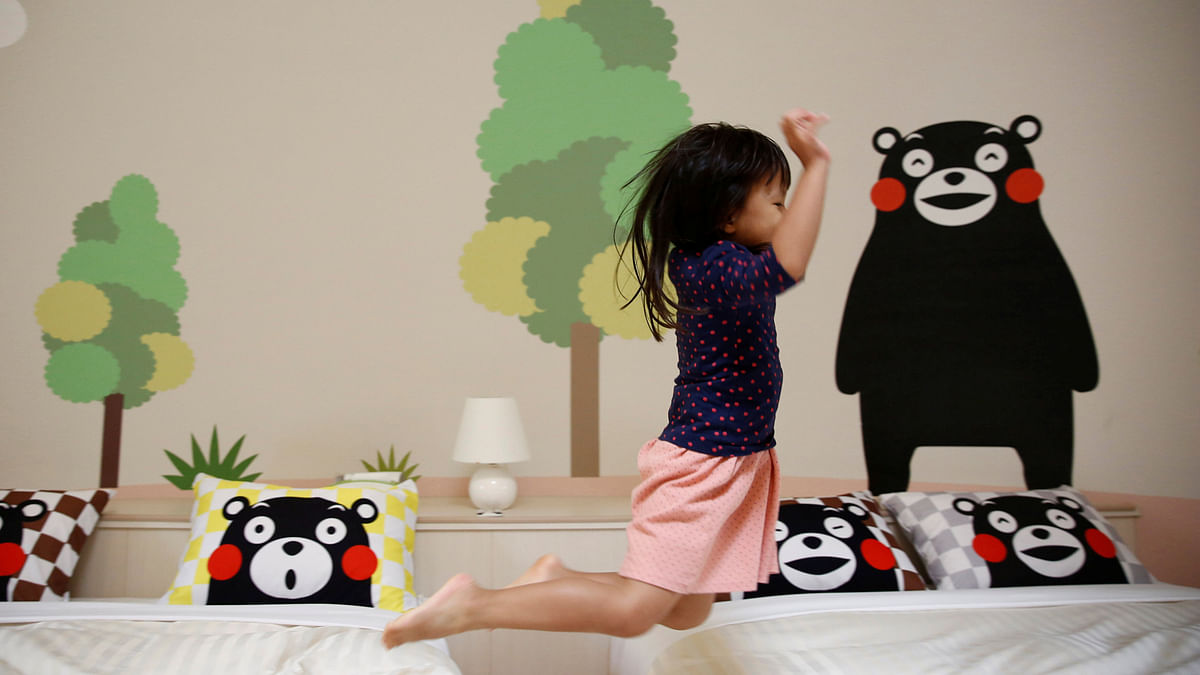 A girl from Singapore jumps on the bed at a quake-resistant dome house decorated with Japan`s popular `Kumamon` bear character after checking in with her family at the Aso Farm Land resort in Aso. Reuters