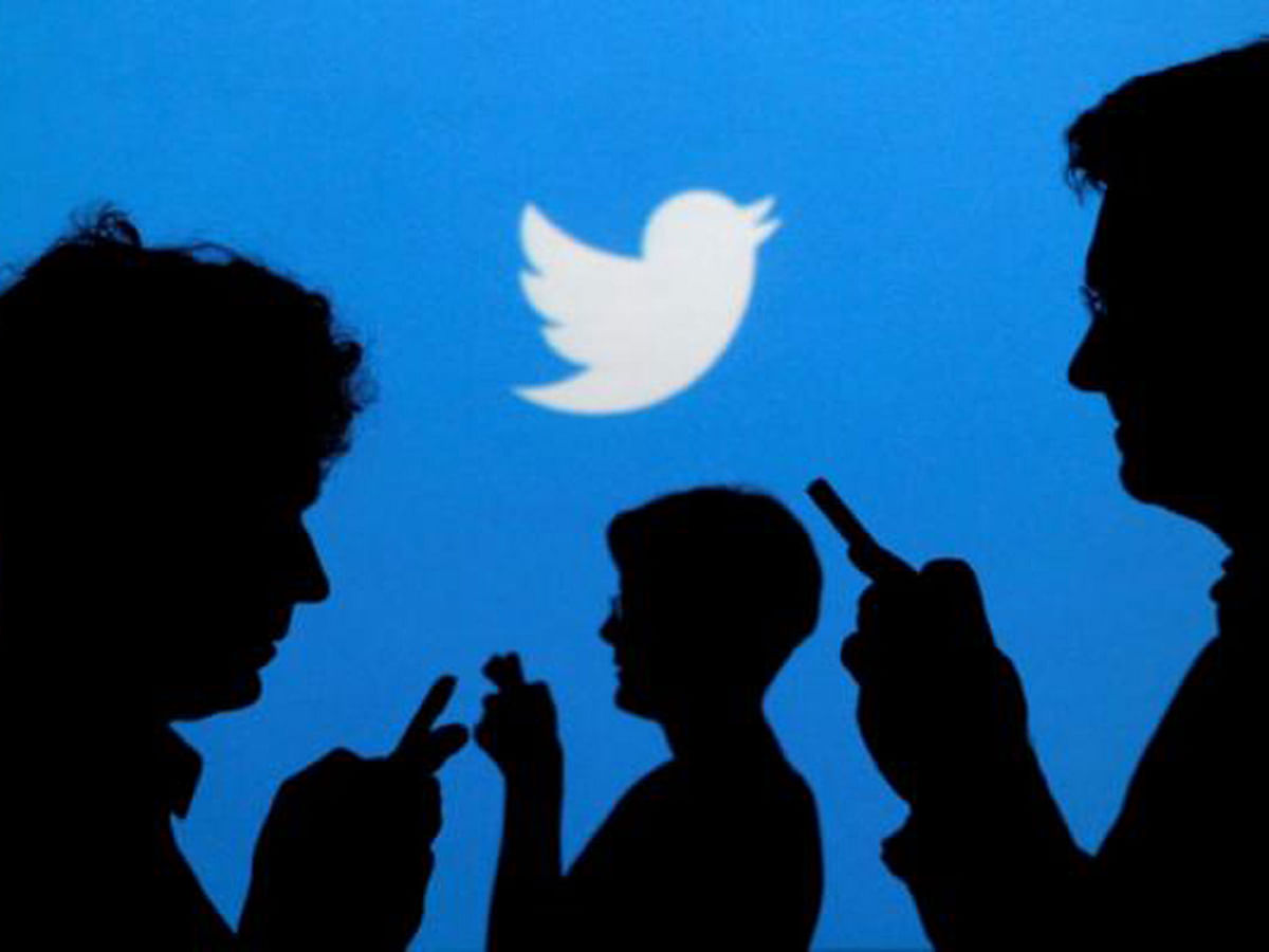 People holding mobile phones are silhouetted against a backdrop projected with the Twitter logo in this illustration picture taken in Warsaw on 27 September 2013. Reuters File Photo