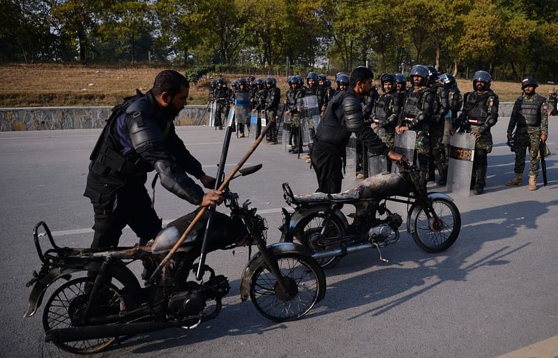 Pakistani riot policemen move their brunt motorbikes torched by protesters of the Tehreek-i-Labaik Yah Rasool Allah Pakistan (TLYRAP) religious group on a blocked street in Islamabad on Saturday. Photo: AFP