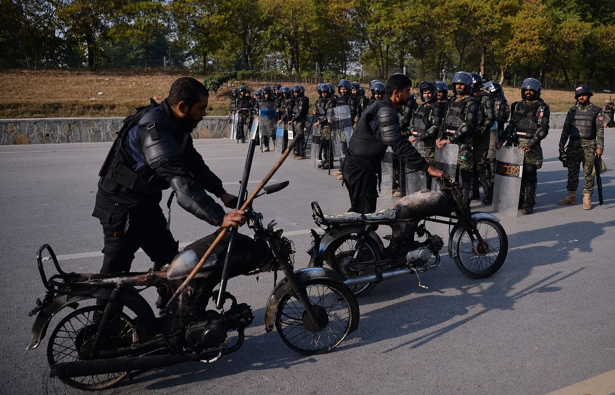 Pakistani riot policemen move their brunt motorbikes torched by protesters of the Tehreek-i-Labaik Yah Rasool Allah Pakistan (TLYRAP) religious group on a blocked street in Islamabad on Saturday. Photo: AFP