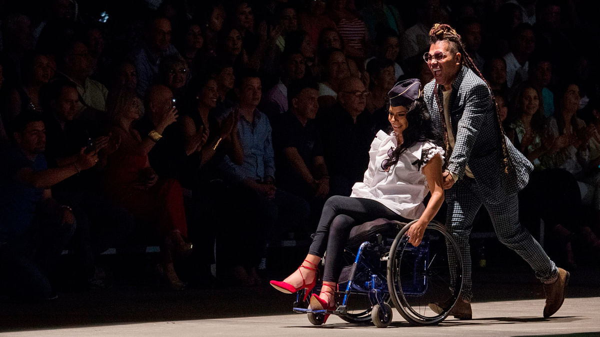 Colombian designer Guio Di Colombia drive a woman in her wheelchair during the Walkway Inclusion fashion show in Cali, Colombia on November 29, 2017. Photo: AFP