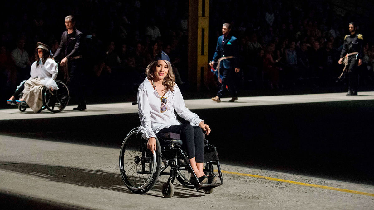 A woman in a wheelchair models a creation by Colombian designer Guio Di Colombia during the Walkway Inclusion fashion show in Cali, Colombia on November 29, 2017. Photo: AFP