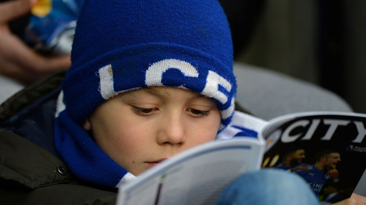 Leicester City fan reads the match day programme in the stadium before the match on 2 December. Photo: Reuters