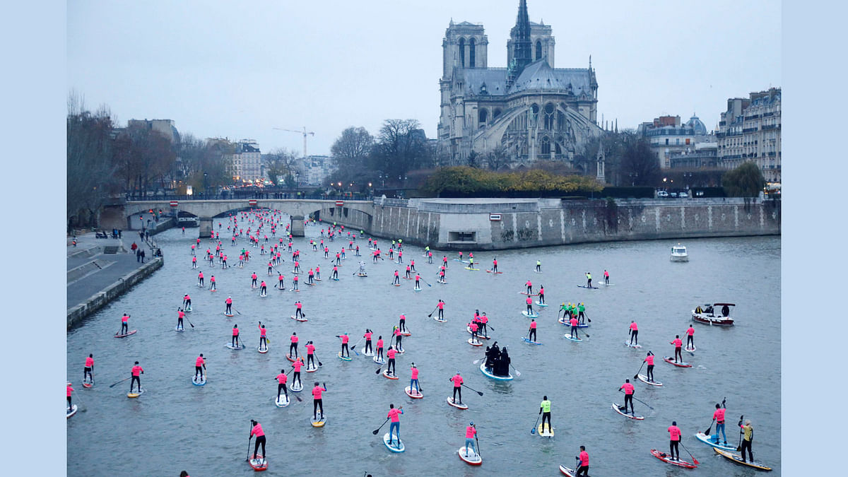 Participants take part in the 8th Edition of the Nautic SUP Paris Crossing stand up paddle competition near the Notre Dame Cathedral on the river Seine in Paris, France. 3 December 2017. Photo: Reuters