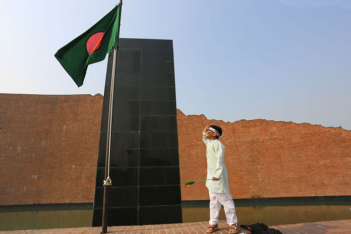 A boy salutes the national flag of Bangladesh at the Martyred Intellectuals’ Mausoleum at Mirpur on the eve of Martyred Intellectual's Day 